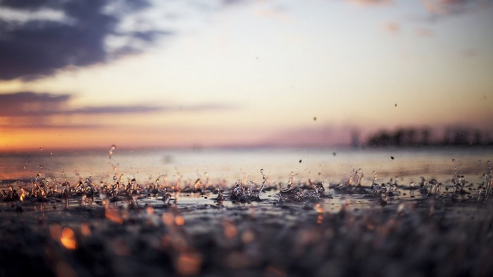 Water drops splashing on surface at sunset