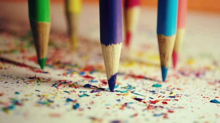 Colorful pencils with shavings on paper