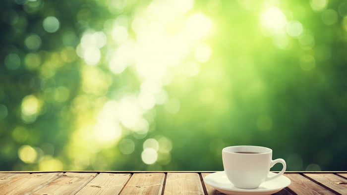 Coffee cup on a wooden table with green bokeh background