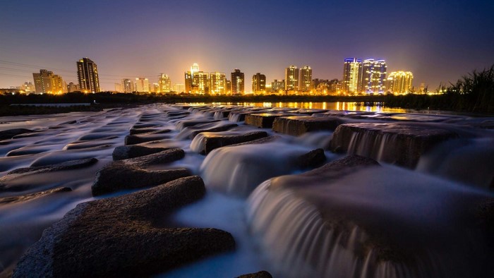 Cityscape at Night with Water Flowing Over Rocks