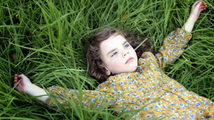 Young girl lying in green grass