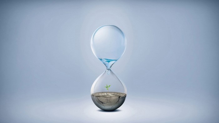 Hourglass with water and plant symbolizing climate change