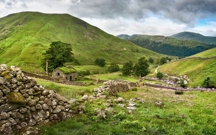 Stone cottage in a green valley with rolling hills