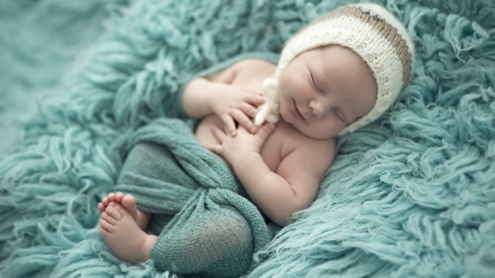 Newborn baby sleeping on a teal fuzzy blanket