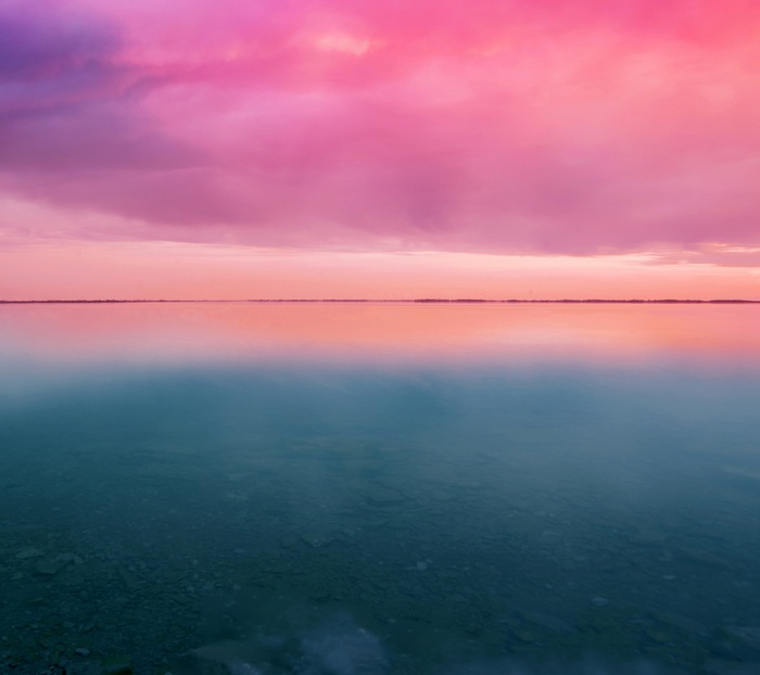 Pink clouds over a calm lake at sunset