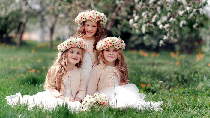 Three young girls wearing flower crowns in a garden