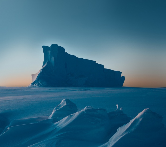 Iceberg at sunset over a frozen landscape