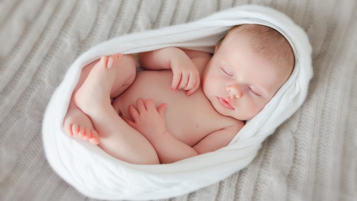 Newborn baby girl sleeping wrapped in a blanket