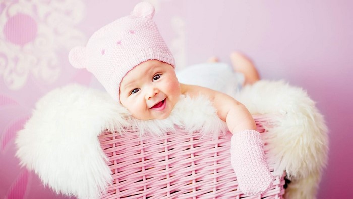 Baby in pink hat and mittens in a basket