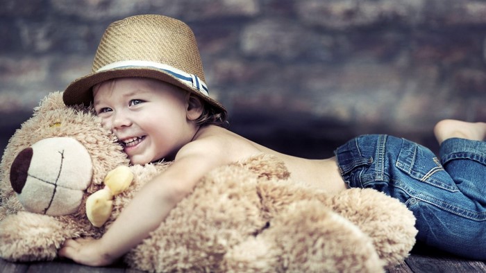Baby boy in hat hugging teddy bear