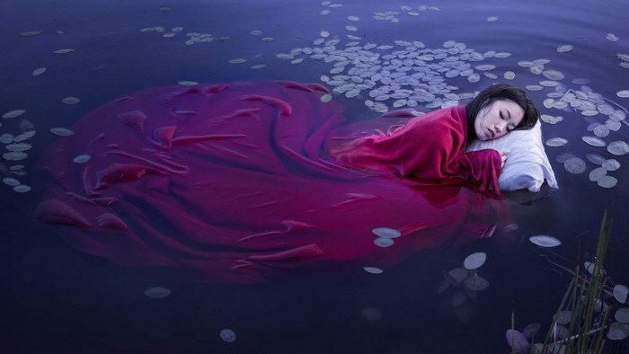 Girl sleeping on a pillow in water with lily pads