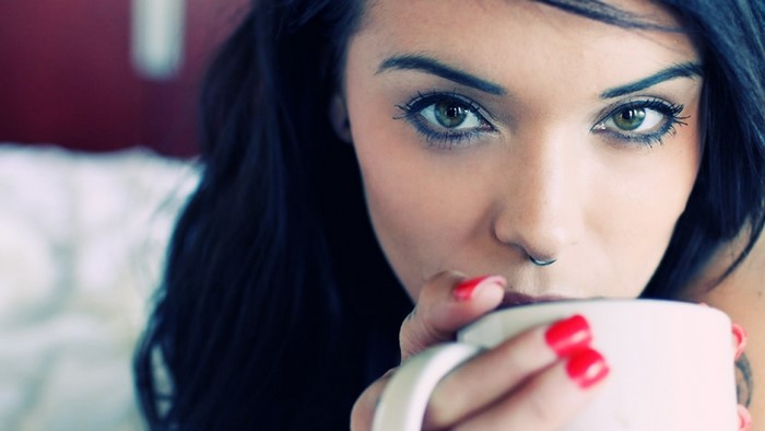 Brunette woman with nose piercing drinking coffee