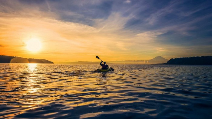 Person kayaking on the sea at sunset