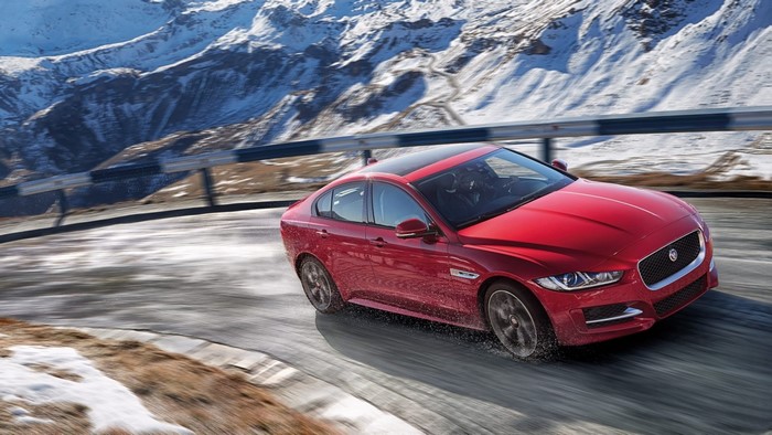 Red Jaguar XE AWD driving on snowy mountain road