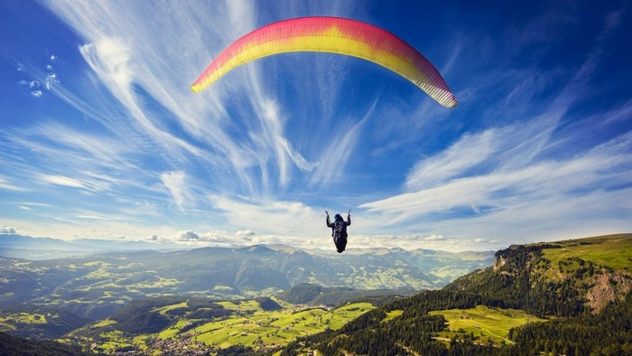 Paraglider flying over mountains and valleys