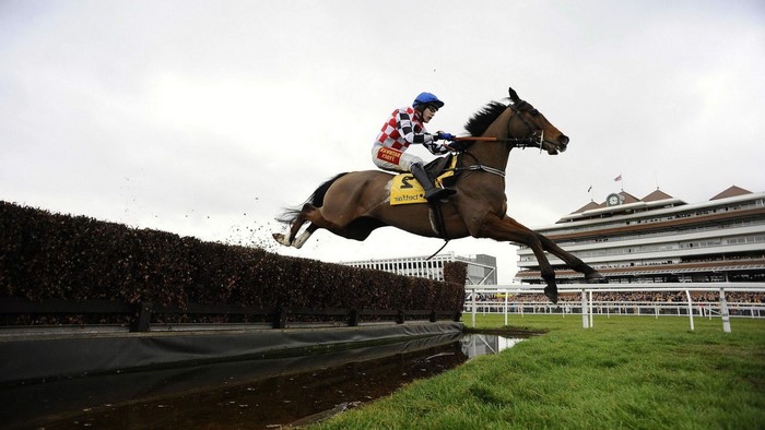 Jockey and horse jumping over a fence at a race track