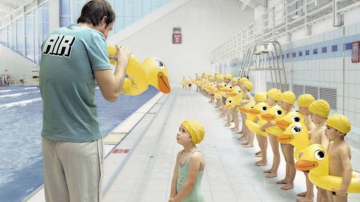 Man inflating duck toy for children in swimming pool