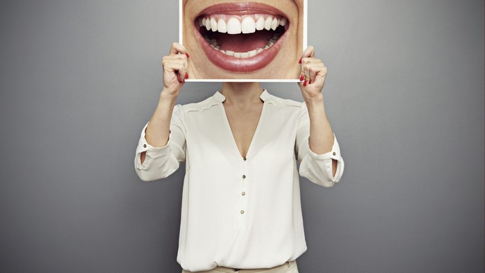 Woman holding a picture of a smiling mouth