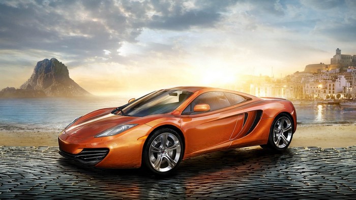 Orange McLaren MP4-12C on a cobblestone path by the sea