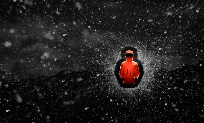 Orange hooded figure in shattering snow