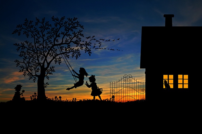 Children playing on swings at sunset silhouette