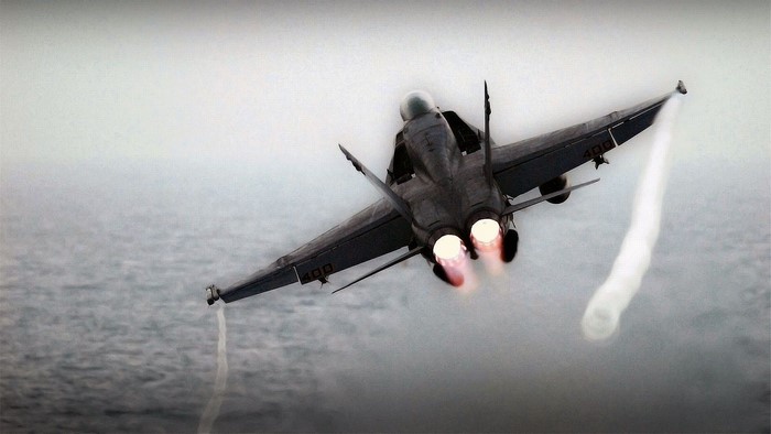 Fighter jet with afterburners over water