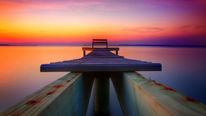 Dock with bench at sunset over water