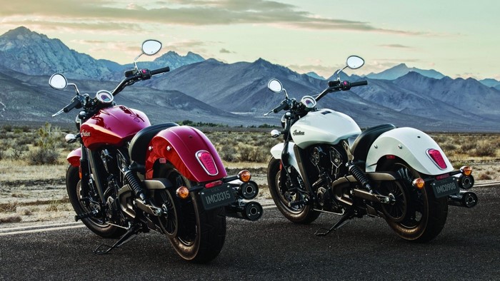 Two Indian Scout motorcycles parked on a road with mountains in the background
