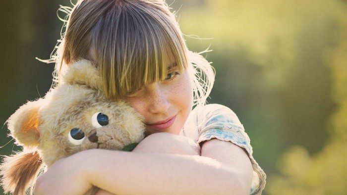 Girl hugging a teddy bear outdoors