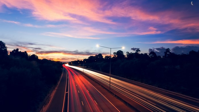 Highway at Dusk with Light Trails and Moon