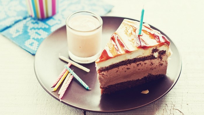 Slice of birthday cake with candles and drink