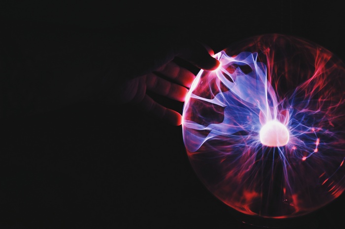 Hand touching a plasma lamp with colorful light