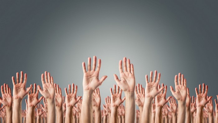Many hands raised in a crowd