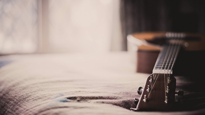 Acoustic guitar on a bed