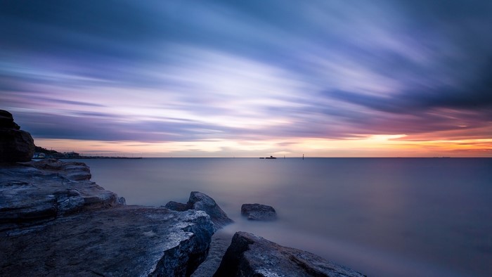 Smooth water and rocks at sunset