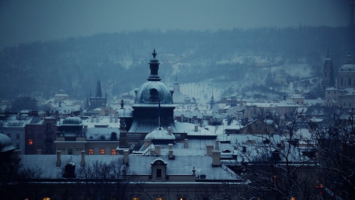 Snowy Prague cityscape with cathedral dome at dusk