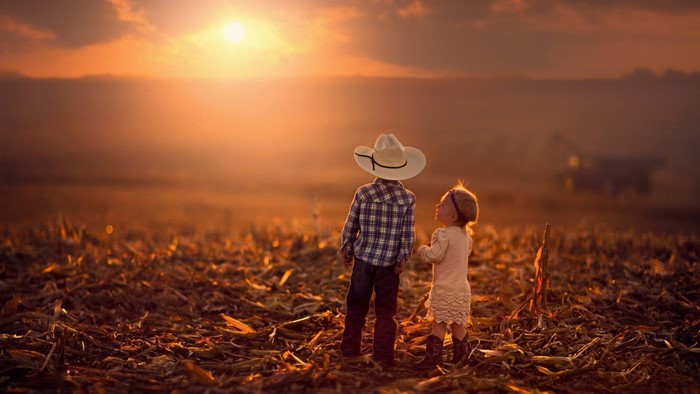 Children in a field at sunset