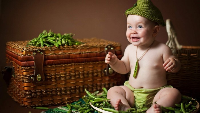 Baby in a pea pod hat with peas