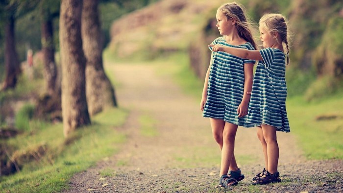 Two young girls in striped dresses on a path