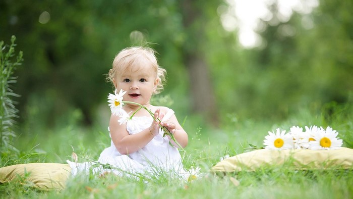 Cute baby girl with daisies in a garden