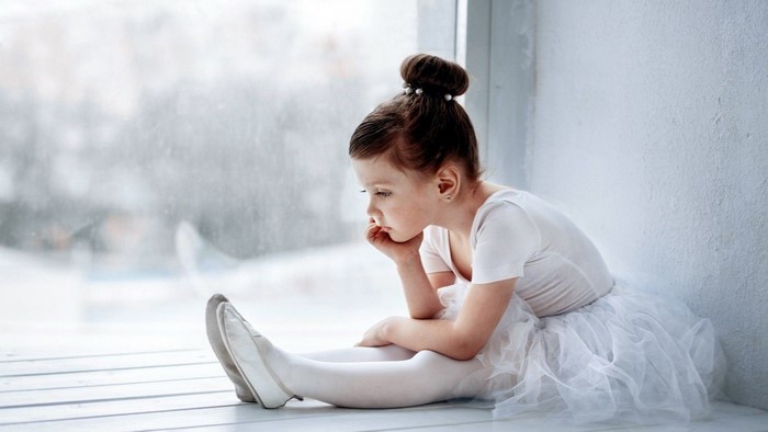 Young ballerina sitting by a window