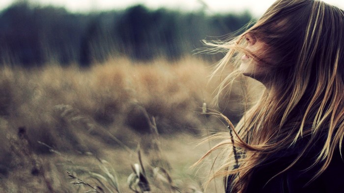 Blonde girl with hair blowing in the wind in a field