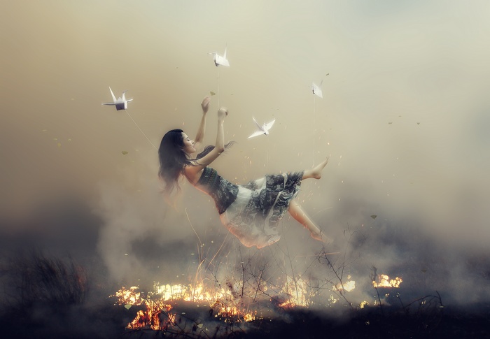 Asian girl falling with paper cranes above fire