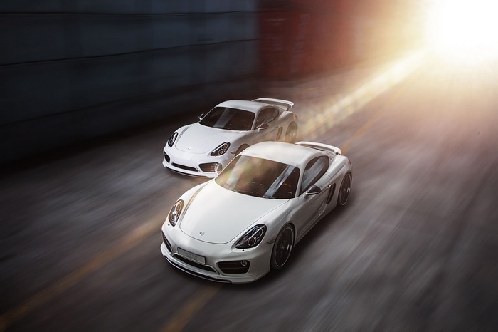 Two white TechArt Porsche Caymans driving on a road