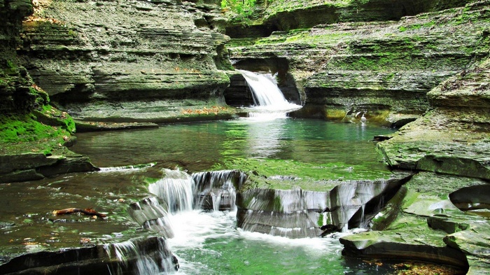Waterfalls cascading into a clear pool in a rocky gorge