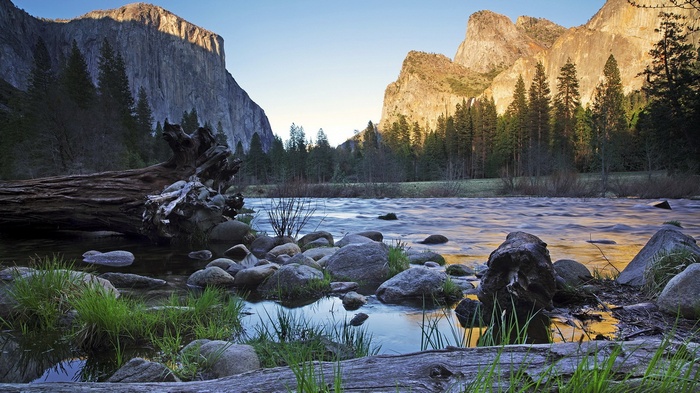 River flowing past rocks and trees with mountains in the background