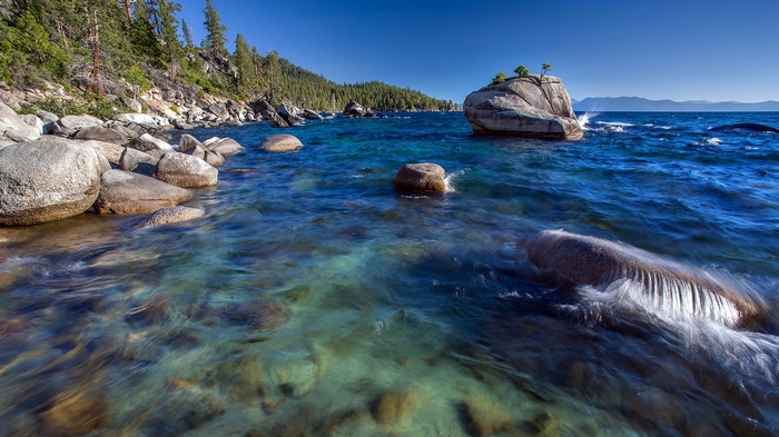 Rocky shoreline with clear blue water and trees