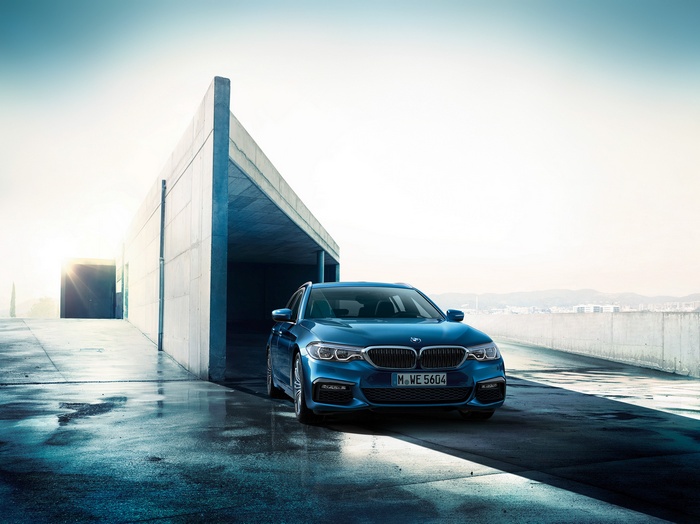 Blue BMW 5 Series Touring G31 parked outside modern building