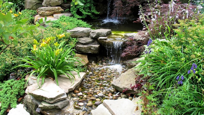 A tiered rock garden with a small waterfall and pond