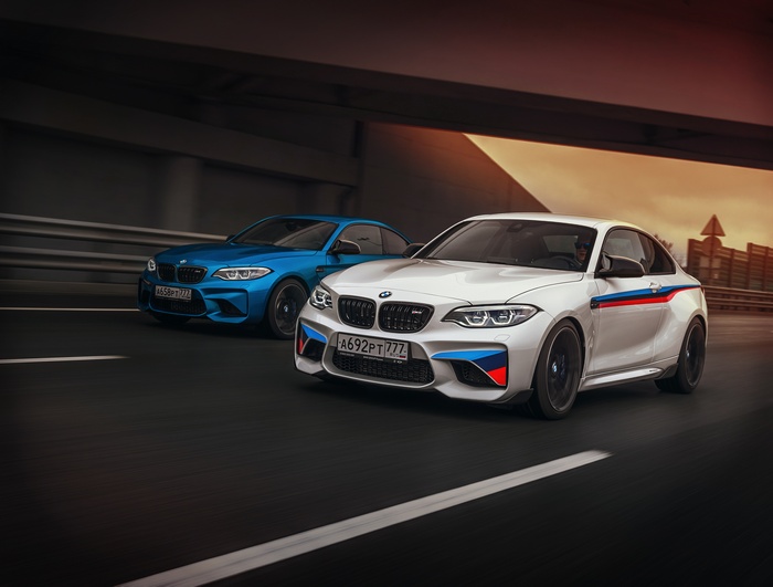 Two BMW M2 cars on a road